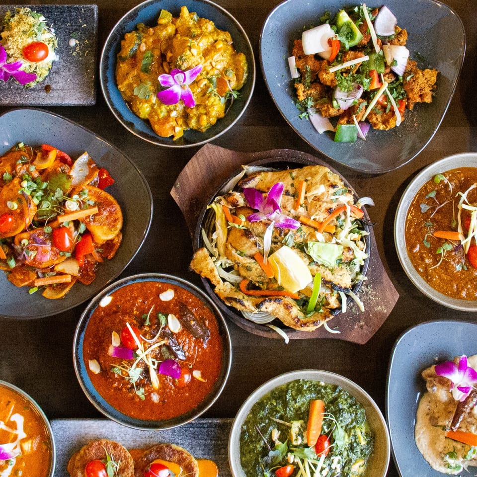 A top-down view of a variety of colorful Indian dishes, including curries, bread, and appetizers.