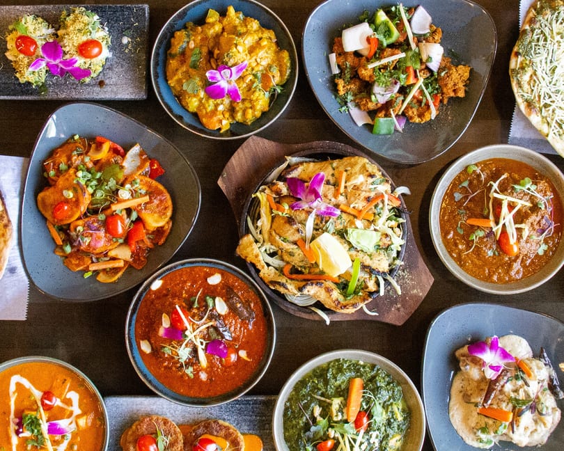 A top-down view of a variety of colorful Indian dishes, including curries, bread, and appetizers.